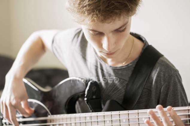 focused_222927622-stock-photo-teenage-boy-playing-guitar-selective